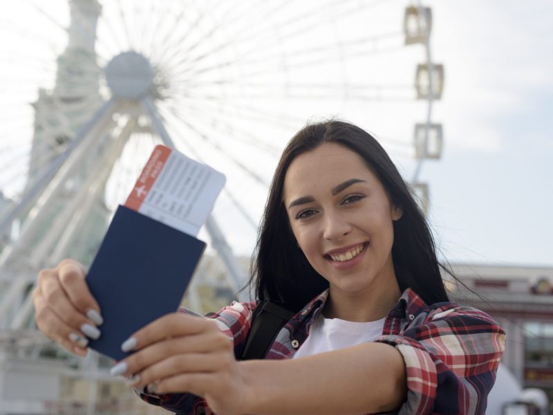portrait-smiling-woman-showing-air-ticket-passport